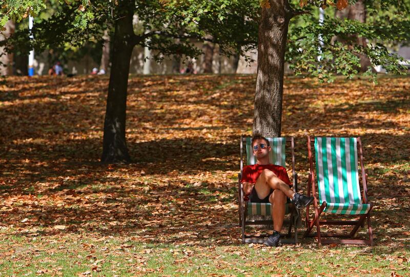 A man sits on a deckchair among brown leaves fallen from the trees in St James's Park, central London, on Wednesday. AFP