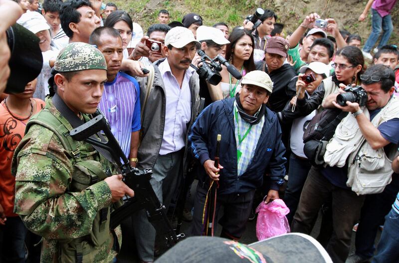 FILE PHOTO: A Revolutionary Armed Forces of Colombia (FARC) member watches a group of indigenous people as they walk past an illegal checkpoint at one of Toribio's main access road, in the province of Cauca, July 11, 2012. Colombian helicopter gunships strafed suspected rebel hideouts and guerrillas set up roadblocks as President Juan Manuel Santos visited the nation's volatile south on Wednesday amid growing criticism that security has deteriorated. REUTERS/Jaime Saldarriaga/File Photo