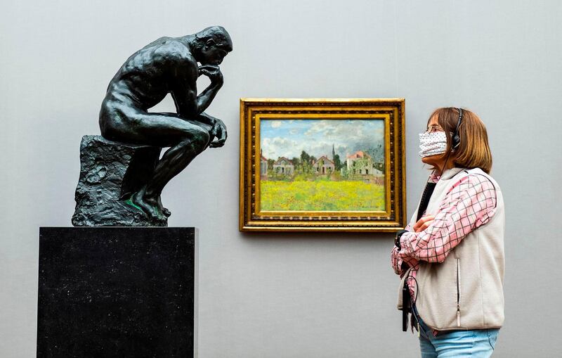 A visitor wearing a face mask looks at French sculptor Auguste Rodin's iconic sculpture "The Thinker" at the Alte Nationalgalerie in Berlin.    AFP