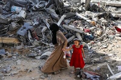 A woman and child walk by mounds of debris after a deadly rescue operation by Israeli forces to free four hostages held by Hamas. Reuters