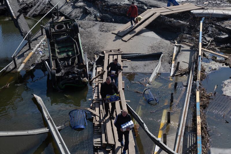 Residents and volunteers cross the destroyed bridge to the city with supplies in Irpin, Ukraine. Getty Images