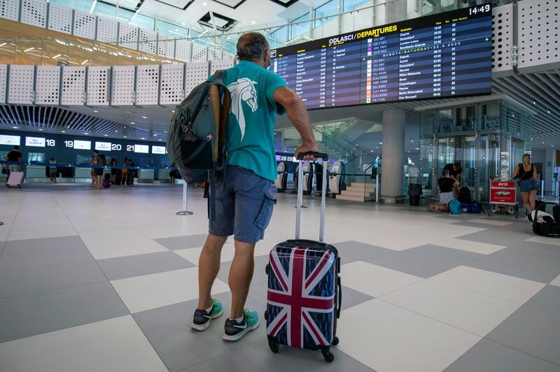 FILE - In this Friday, Aug. 21, 2021 file photo, a passenger inspects the departures timetable at the international airport in Split, Croatia. Airlines and holiday providers on Friday, June 25, 2021 expressed frustration with the U.K.â€™s plans to ease travel restrictions, saying uncertainty about how and when the new rules will be implemented make it difficult for people to book summer vacations. (AP Photo/Miroslav Lelas, File)