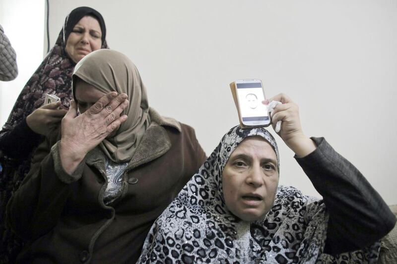 The mother of Palestinian Mutaz Hijazi, right, holds a picture of him over a phone over her head at their family house in the Abu Tor neighbourhood of east Jerusalem on October 30, 2014.  Israeli police shot dead Hejazi, a 33-year-old Palestinian suspected of shooting a far-right Jewish activist. Ammar Awad / Reuters