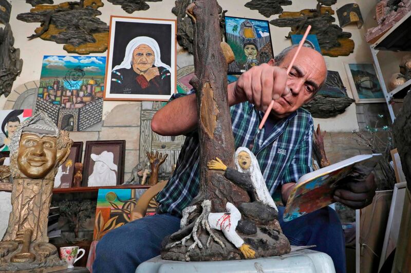Palestinian artist Naim Al Khatib paints his sculpture of a woman hugging an olive tree at his workshop in the West Bank village of Dura, southwest of Hebron. AFP