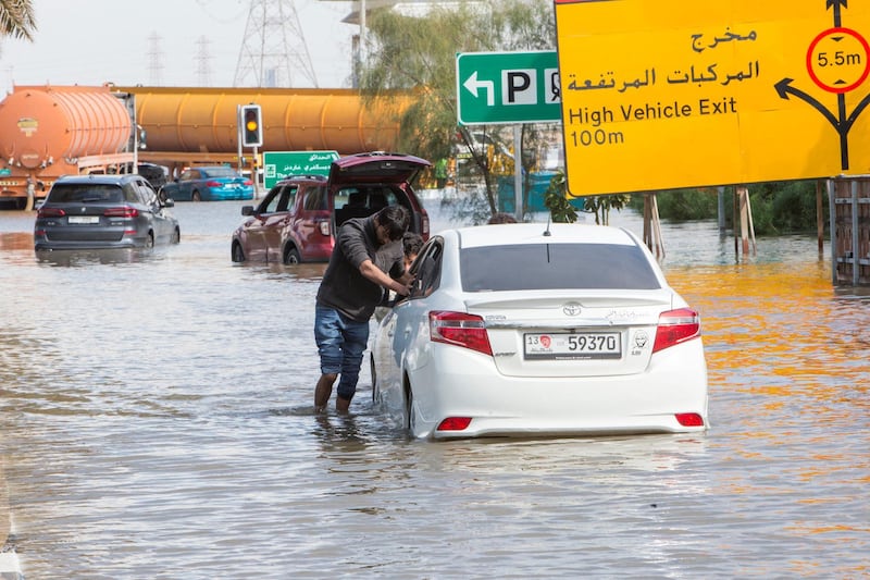 Dubai, United Arab Emirates - A car owner helped by some friends helplessly pushing his car out of the flooded street closed to Batuta and Discover Gardens streets.  Ruel Pableo for The National