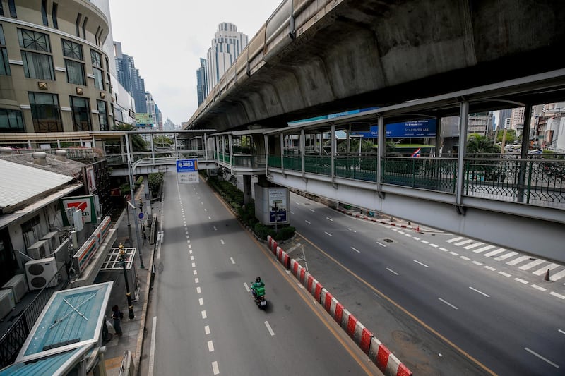 A food delivery man rides a motorcycle on a nearly empty street in Bangkok on May 1, 2021 as the Thai capital entered a partial lockdown in a bid to contain the rise in Covid-19 infections. EPA