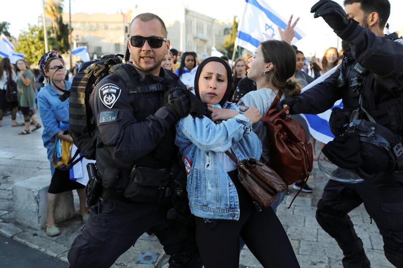 Israeli police removes a Palestinian woman from the area as youth from far-right Israeli groups participate in a flag-waving procession at Damascus Gate, just outside Jerusalem's Old City June 15, 2021. REUTERS/Ammar Awad