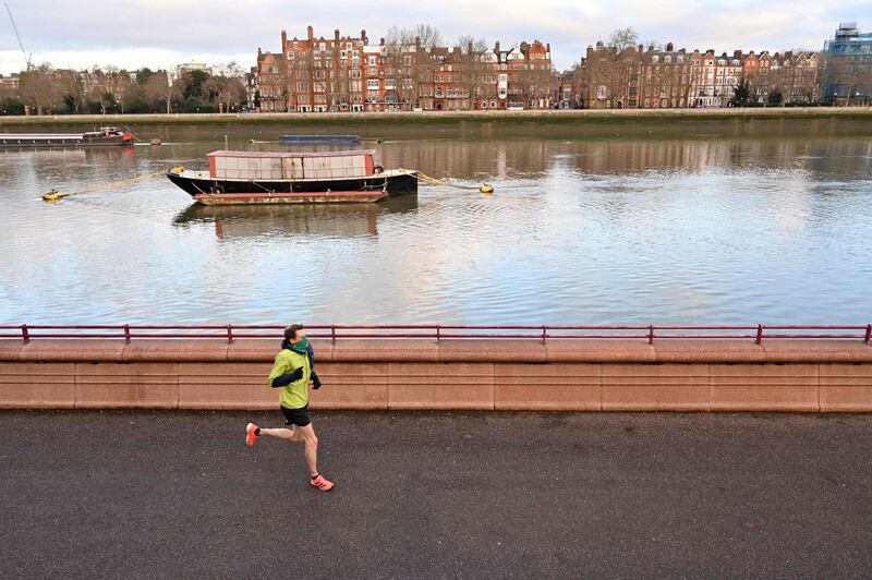 A person jogs along the river front at sunrise as they exercise in Battersea Park in London. AFP