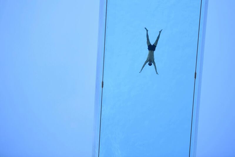 A man swims across the Sky Pool, a transparent swimming pool bridge that spans between two residential blocks in the Nine Elms area of London, on Friday, April 23. AP