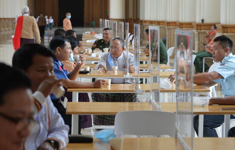 Members of Myanmar's parliament are pictured on a break abiding by social distancing rules with plastic dividers at tables at the Pyidaungsu Hluttaw parliament building in Naypyidaw. AFP