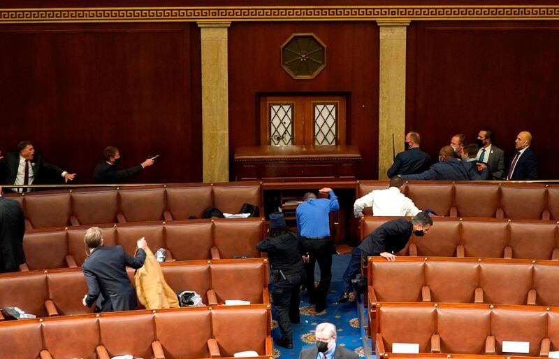 U.S. Capitol police officers point their guns at a door that was vandalized in the House Chamber during a joint session of Congress. AFP