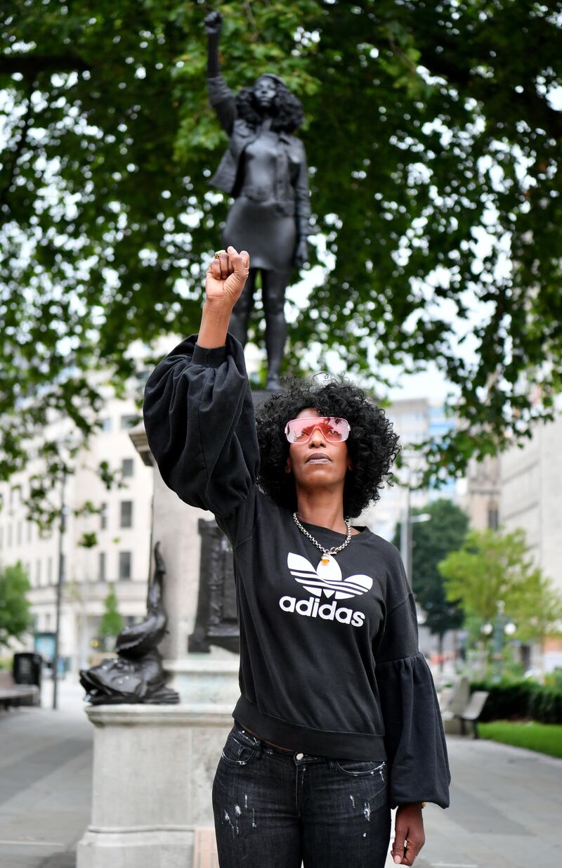 Black Lives Matter protester Jen Reid poses for a photograph in front of the sculpture of herself. Getty Images