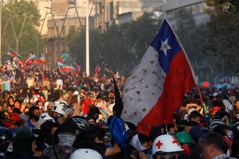SANTIAGO, CHILE - NOVEMBER 18: Demonstrators clash with riot police during protests against president Sebastián Piñera on November 18, 2019 in Santiago, Chile. Yesterday President of Chile Sebastian Piñera announced Chilean lawmakers agreed on calling a referendum in April 2020 to replace the current constitution, written and approved during General Augusto Pinochet's military dictatorship in 1980. People will be asked if they approve they idea of a new Magna Carta and if current lawmakers should work on the redraft of the document. (Photo by Marcelo Hernandez/Getty Images)