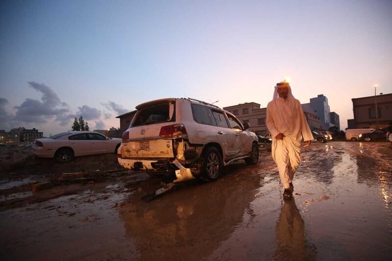 A Kuwaiti man walks in flooded street next to damaged vehicles following heavy rain in al-Fahahil district south of the capital Kouwait on November 10, 2018.  / AFP / Yasser Al-Zayyat
