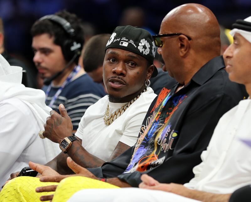 Rapper DaBaby, left, talks to Steve Harvey in their courtside seats during the second pre-season game