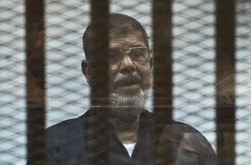 (FILES) In this file photo taken on June 16, 2015 Egypt's ousted Islamist president Mohamed Morsi stands behind the bars during his trial in Cairo. Former Egyptian President Mohamed Morsi died on June 17, 2019 in a Cairo hospital after fainting in a court session, a judicial and security source said. / AFP / Khaled DESOUKI
