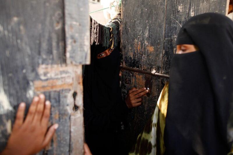 Women stand by the door of their hut.