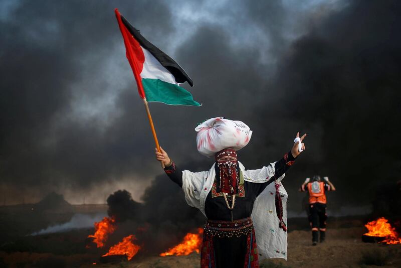 A woman holds a Palestinian flag during a protest calling for lifting the Israeli blockade on Gaza and demand the right to return to their homeland, at the Israel-Gaza border fence, east of Gaza City September 14, 2018. REUTERS/Mohammed Salem      TPX IMAGES OF THE DAY