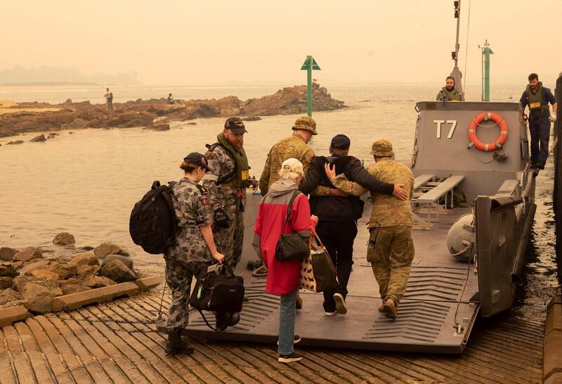 Evacuees board landing craft to be ferried out to the navy's HMAS Choules. AP