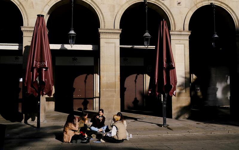 Women eat while sitting in front of a closed restaurant at the empty Plaza Reial in Barcelona. Reuters
