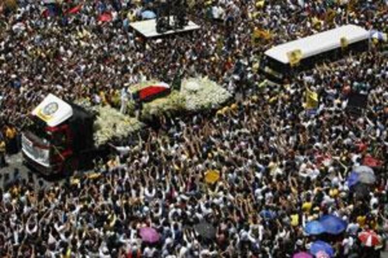 A truck carrying the casket of late former president Corazon Aquino passes thousands of people along the main street of Makati's financial business district of Manila on August 3, 2009.