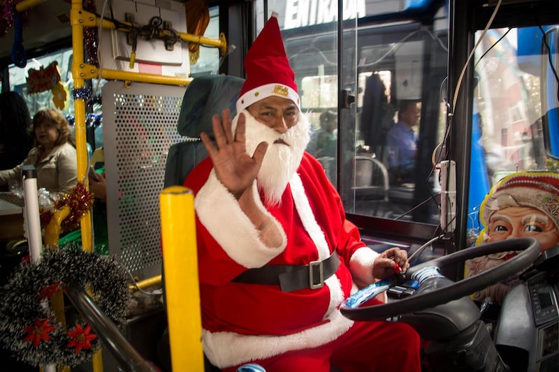 Ecuadorean Carlos Yanez waves as he drives a public transport bus dressed up as Santa Claus in Quito. AFP