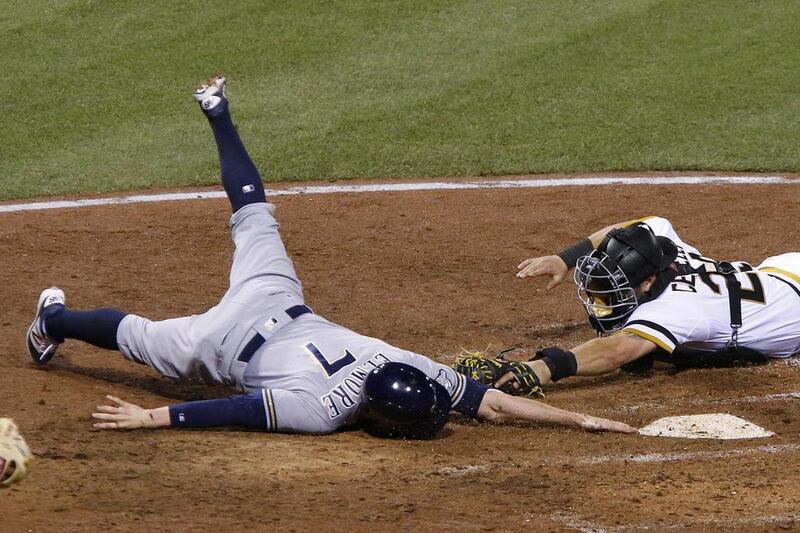 Milwaukee Brewers’ Jake Elmore (7) reaches to touch home plate after sliding around the tag by Pittsburgh Pirates catcher Francisco Cervelli during the eighth inning of a baseball game in Pittsburgh. Elmore was called safe, the Pirates challenged, and safe call stood. The Brewers won 7-4. Gene J. Puskar / AP Photo