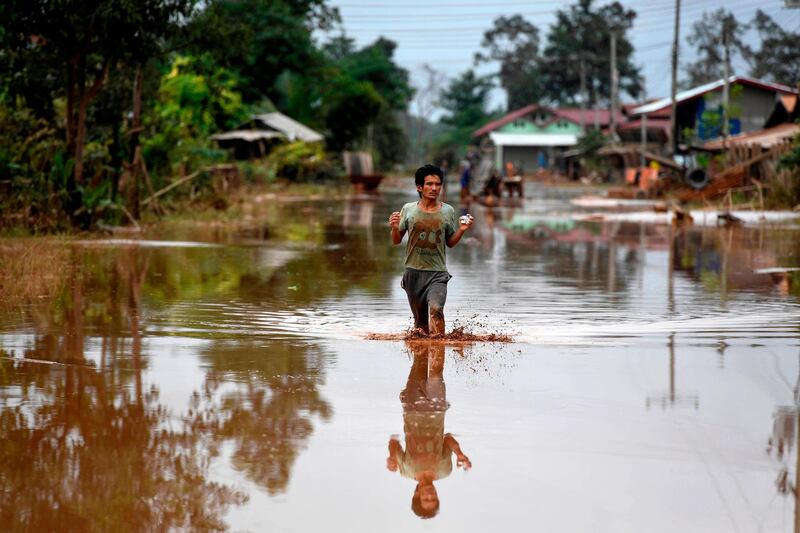 A man wades through a flooded road at a village in Sanamxai, Attapeu province. AFP