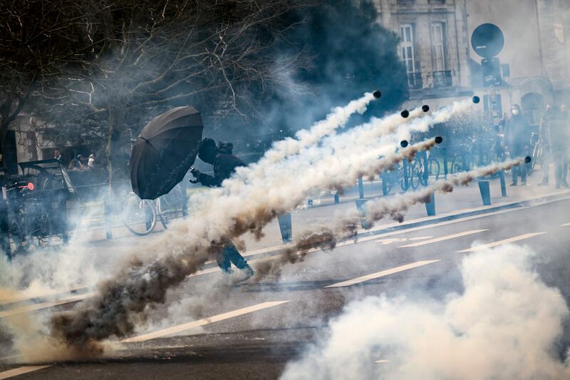 An umbrella shields a protester from tear gas at a rally against the government's proposed pensions overhaul, in Nantes, France. AFP

