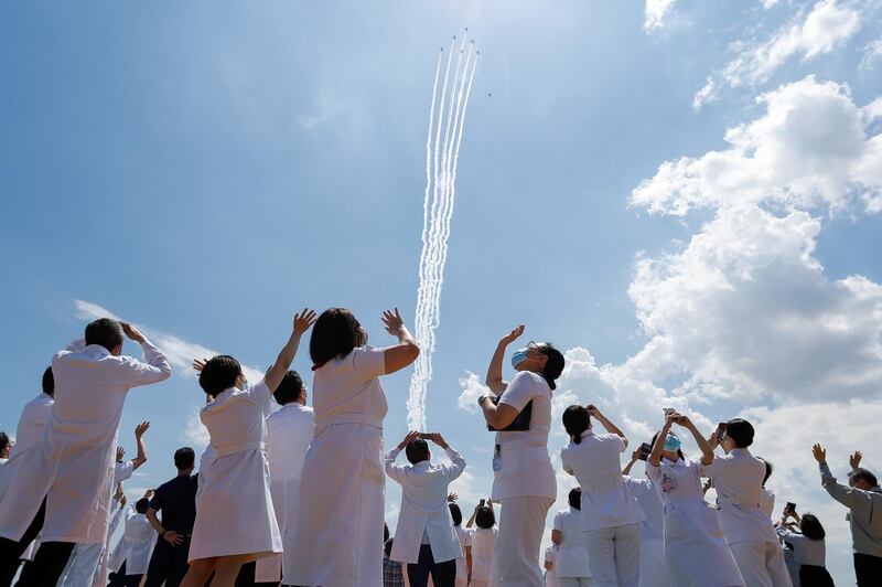 Medical workers react as they watch the Blue-Impulse aerobatic team of Japan Air Self-Defense Force fly over the Self-Defense Forces Central Hospital in Tokyo, Japan. Reuters