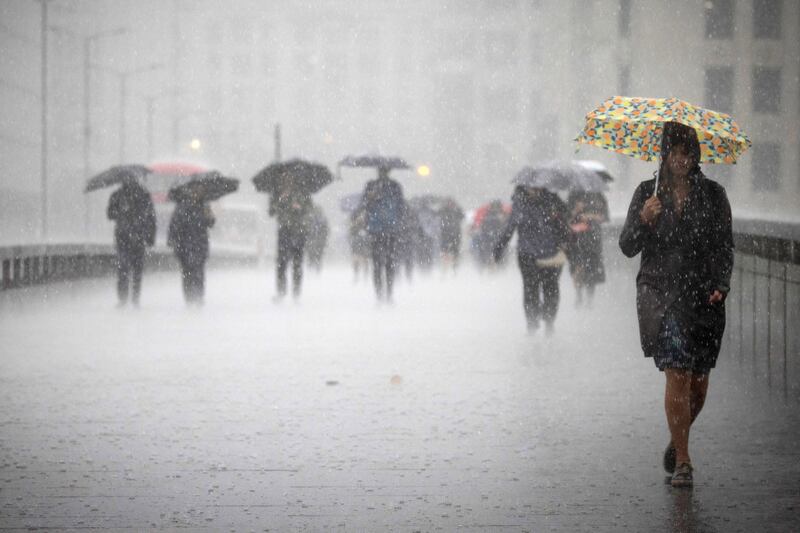 People cross London Bridge during heavy rainfall. The British Met Office has warned of widespread flash floods with thunderstorms likely across the country. EPA 