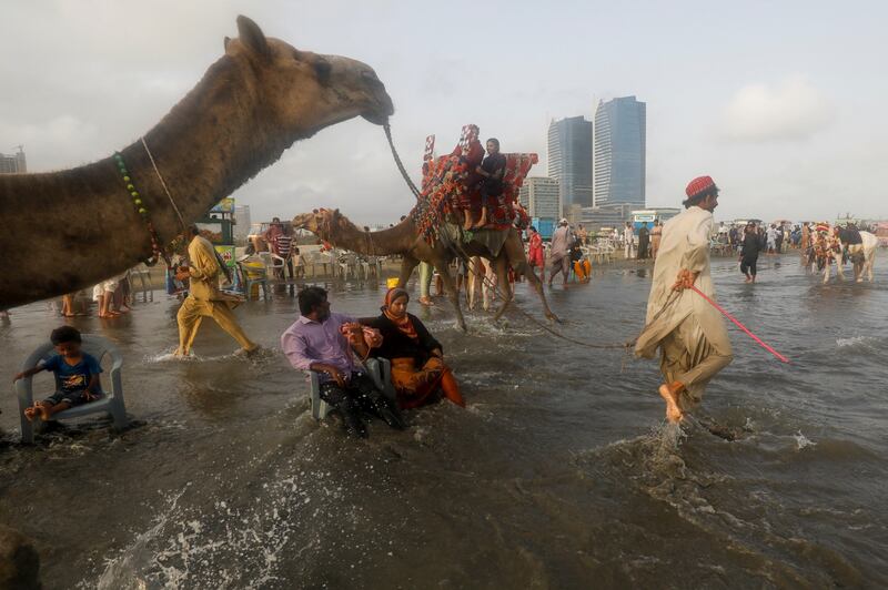 People sit on chairs in the sea to cool off during a hot day in Karachi, Pakistan. Reuters