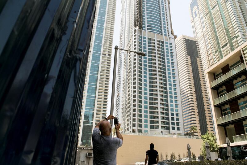 DUBAI, UNITED ARAB EMIRATES - AUG 4: 

A man takes a photo of Dubai Marina's Torch Tower, one of the world's tallest residential buildings, after a fire started last night.


(Photo by Reem Mohammed/The National)

Section: NA