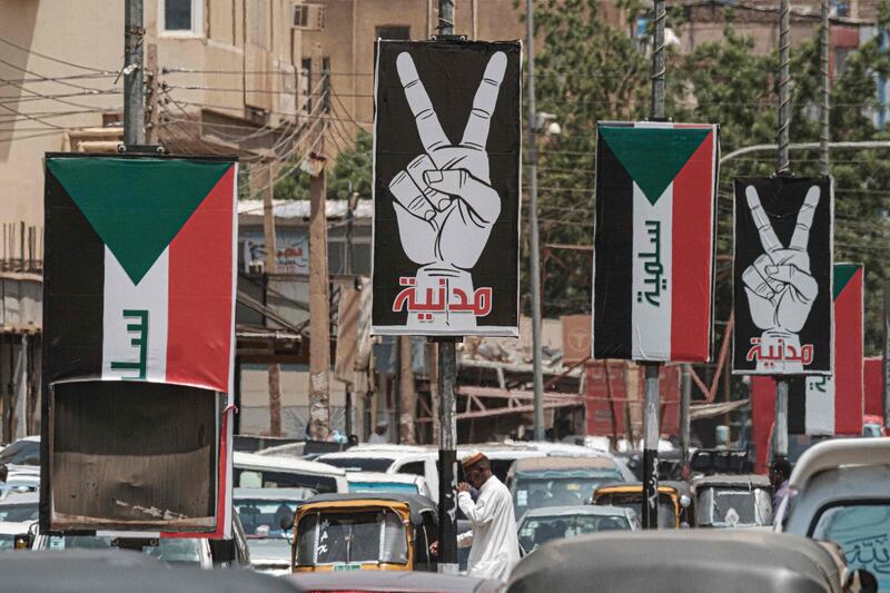 This picture taken shows placards showing the victory gesture with the Arabic word "civilian" and others of the Sudanese flag with the word "peaceful" along a street in the Sudanese capital Khartoum.  AFP