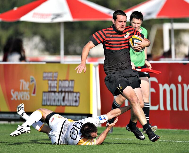 Abu Dhabi Saracens' Nathan Ramsey, in red, evades a tackle from a Dubai Hurricanes defender. Saracens went on to win 21-18 at The Sevens in Dubai City, Dubai on February 28, 2014. Jeff Topping for The National