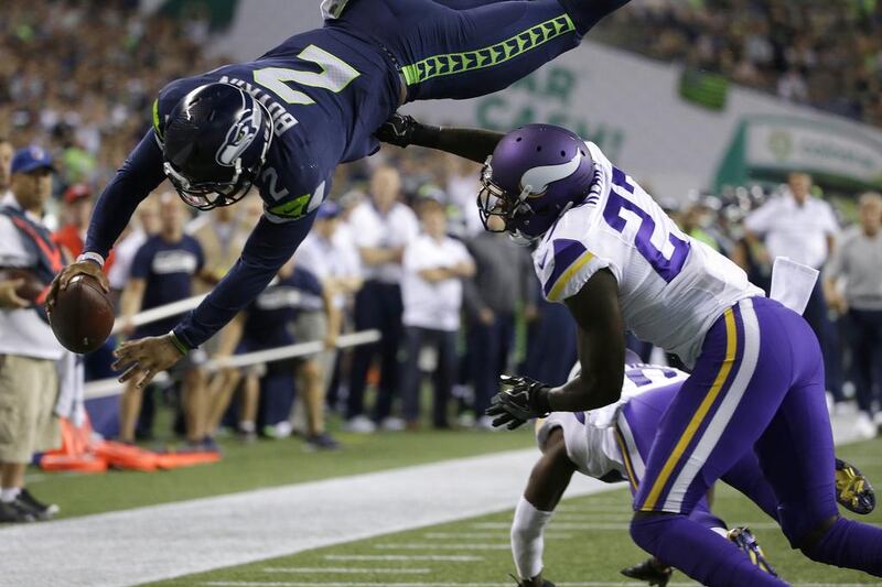 Seattle Seahawks quarterback Trevone Boykin dives to score a 2-point conversion over Minnesota Vikings safety Jayron Kearse, right, during their pre-season NFL football game. Elaine Thompson / AP Photo