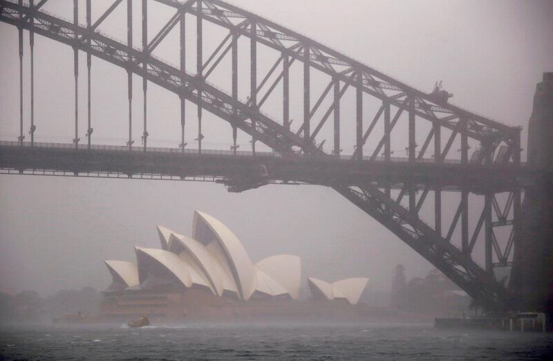A boat passes under the Sydney Harbour Bridge and in front of the Sydney Opera House as strong winds and heavy rain. Reuters