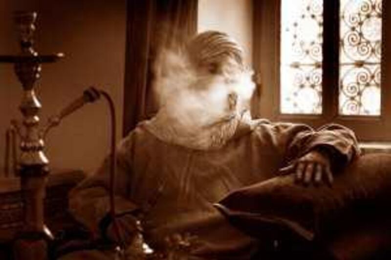 Mature man with hookah pipe blowing out smoke (B&W)