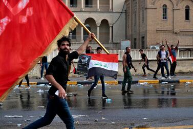 Protestors wave flags and hold a poster of Lt Gen Abdul Wahab Al Saadi during a protest in Baghdad, Iraq. AP Photo