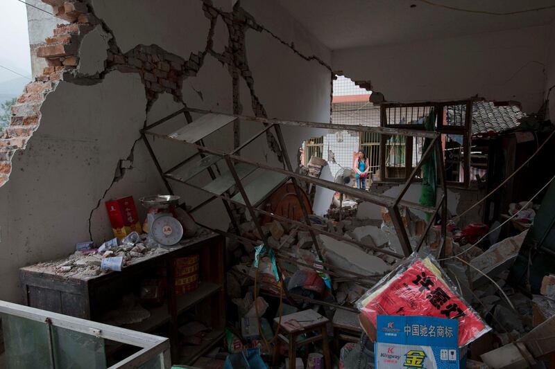 A woman walks past a shop destroyed by an earthquake in Gucheng village in Longmen county of southwestern China's Sichuan province, Sunday, April 21, 2013. Rescuers and relief teams struggled to rush supplies into the rural hills of China's Sichuan province Sunday after the earthquake prompted frightened survivors to spend a night in cars, tents and makeshift shelters. (AP Photo/Ng Han Guan) *** Local Caption ***  China Earthquake.JPEG-046fe.jpg