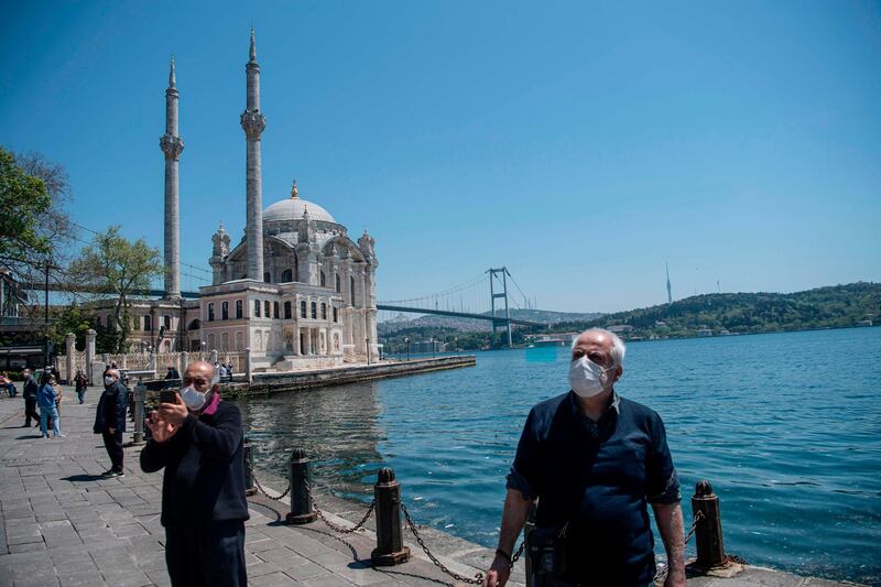 Elderly people wearing protective face masks, stroll along the seaside on May 10, 2020, at Ortakoy in Istanbul, after a month and a half of lockdown restrictions aimed at stemming the spread of the novel coronavirus, COVID-19. Turkish people aged 65 and over on May 10, 2020, described their joy after the government allowed them to go outside for the first time in nearly two months in an easing of the coronavirus restrictions. While 24 provinces including Ankara and Istanbul are subject to a weekend lockdown, President Recep Tayyip Erdogan said last week senior citizens could leave their homes between 0800 GMT and 1200 GMT on May 10.  / AFP / Ozan KOSE
