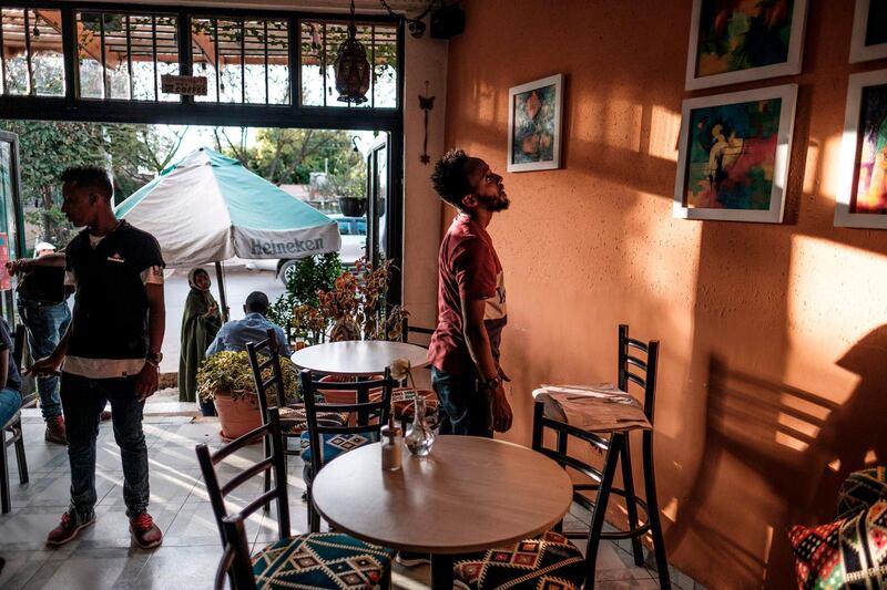 Eritrean painter Noah Mulubrhan 35, (R) looks at hanged paintings as he prepares an exhibition in a local coffee shop in Addis Ababa. AFP