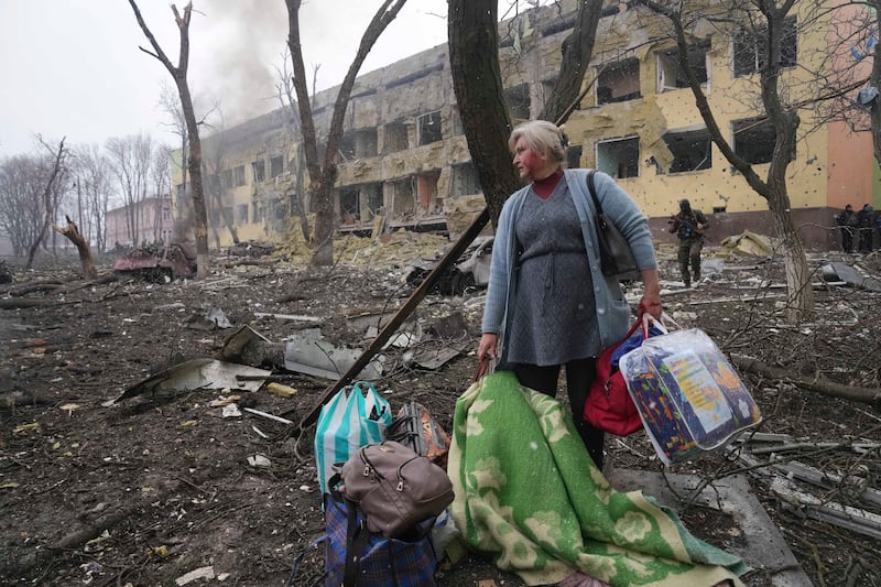 A woman waits outside a maternity and children's hospital damaged by shelling in Mariupol, Ukraine. AP