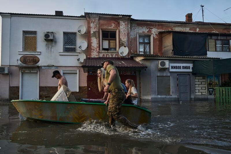Rescue workers attempt to tow boats carrying residents being evacuated from a flooded district. AP