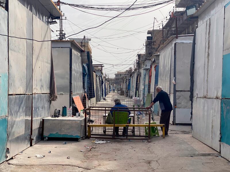 People sit near shops that are closed to help prevent the spread of the coronavirus at a nearly empty market in the eastern suburb of Baghdad. AP Photo