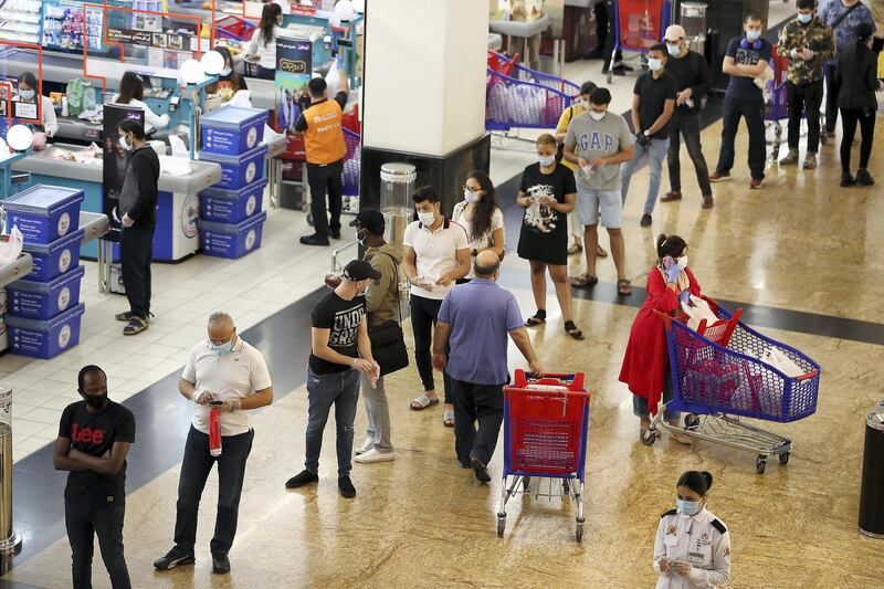 DUBAI, UNITED ARAB EMIRATES , April 29 – 2020 :- People standing in a queue and wearing protective face mask to prevent the spread of the coronavirus outside the Carrefour Hypermarket at Mall of the Emirates in Dubai. Authorities ease the restriction for the residents in Dubai. At present mall opening timing is 12:00 pm to 10:00 pm. Carrefour timing is 9:00 am to 10:00 pm. (Pawan Singh / The National) For News/Standalone/Online. Story by Patrick