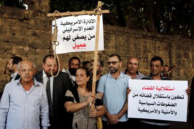 Former inmates of Khiam prison hold placards in Arabic that read, "who listens to the American administration and the Israeli enemy. He is an agent," left, and "the independence of justice is when the judiciary is independent from American political and security pressures," right, during a sit-in near a military court where an arrest warrant was issued for Lebanese-American Amer Fakhoury, who confessed he'd worked for Israel during its occupation of Lebanon for nearly two decades, in Beirut, Lebanon, Tuesday, Sept. 17, 2019. Fakhoury was detained after returning to his native Lebanon from the United States earlier this month. (AP Photo/Bilal Hussein)