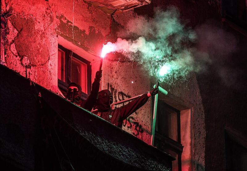 Protesters light flares on the balcony of a squatted house in the Friedrichshain district prior to May Day in Berlin, Germany.  EPA