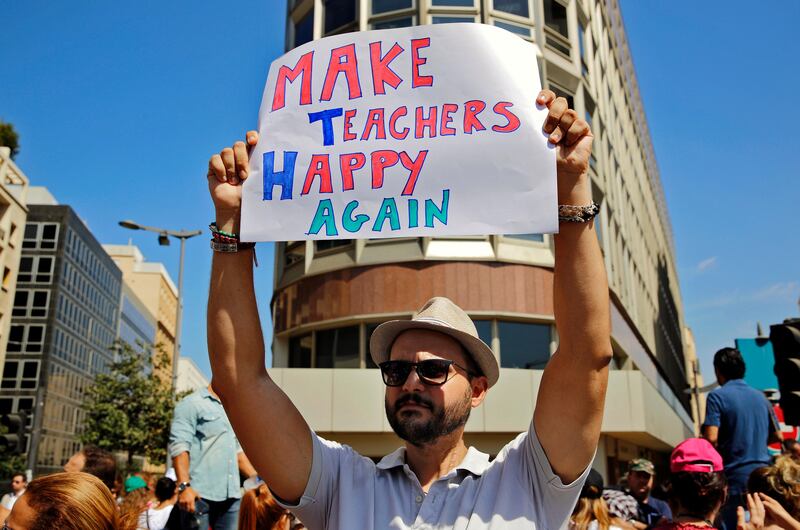An protester holds a placard during a rally in front of the government building in downtown Beirut, Lebanon, Tuesday, Sept. 26, 2017. Lebanon's civil servants are on strike to pressure the government to pay them recently approved wage hikes amid a new crisis over how to finance the wages bill, estimated at $800 million. (AP Photo/Bilal Hussein)