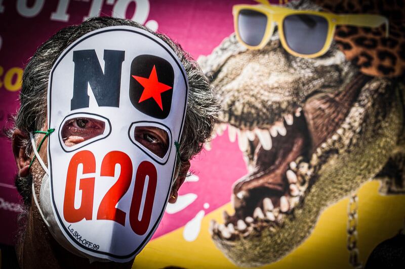 A protester wears a mask bearing the slogan 'No G20'.